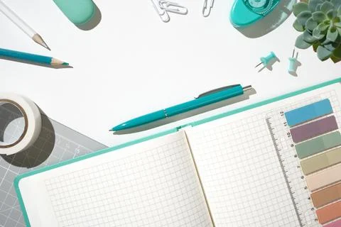 Open notebook on grey cutting mat with pencils, clips, and scissors for pla.. Stock Photos