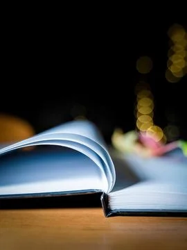An open notebook or diary with white pages against bokeh lights in the dark Foto stock