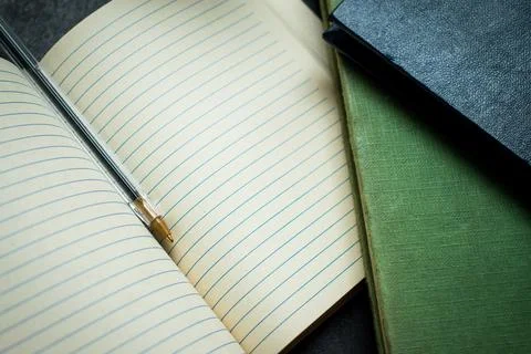Open Notebook With Pen On Desk, Lined Pages, And Stacks Of Books For Study .. Foto stock