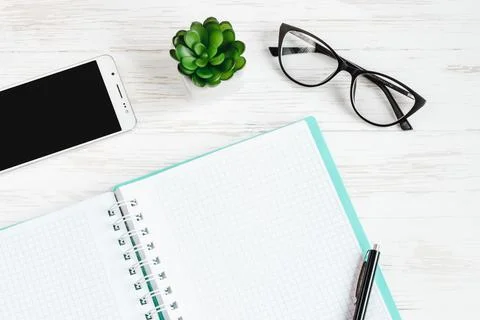 Open notebook, pen, glasses, mobile phone, a cup of coffee on a white wooden  Stock Photos