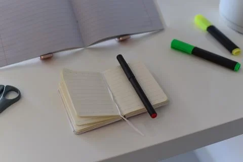 Open notebook with pen on white desk, tidy workspace, high-angle close-up Foto stock