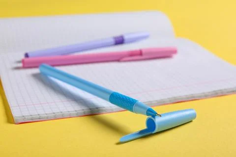 Open notebook with pens on yellow background Stock Photos