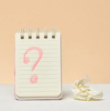 An open notebook with a question mark drawn in red pencil next to a crumple.. Stock Photos