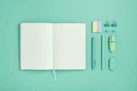 Open notebook with space for your text with green stationery on turquoise bac Stock Photos