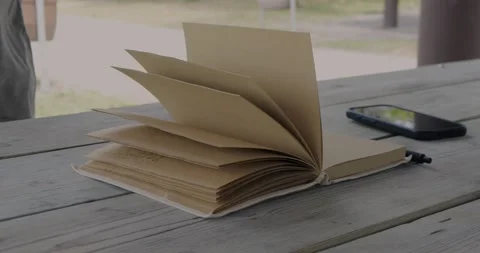 Open Notebook With Turning Pages and Smartphone on Wooden... Stock Footage 332807927