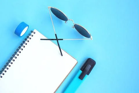 Open notebook with white blank pages and sunglasses on a bright blue backgrou Stock Photos
