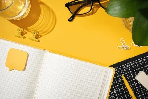 Open notebook on yellow background with glasses, pen, and office supplies. .. Stock Photos