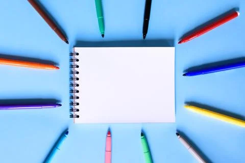 Open notepad and open multicolored markers on the blue background. Place for Stock Photos