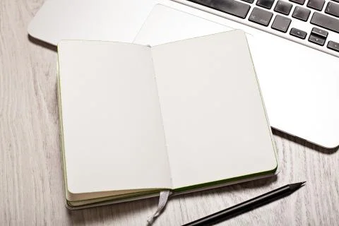 Open notepad with blank pages on white table with laptop Stock Photos