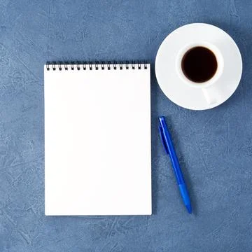 Open notepad with clean white page, pen and coffee cup on aged dark blue stone Stock Photos