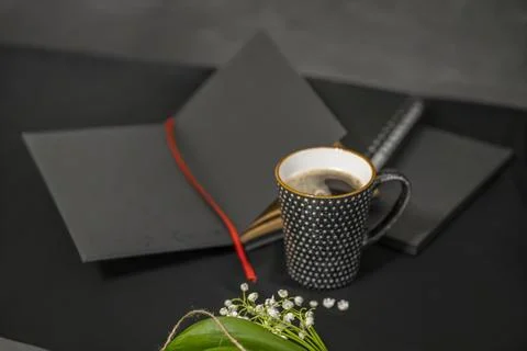 Open notepad, cup of coffee and lilies of the valley on a black background. Stock-Fotos