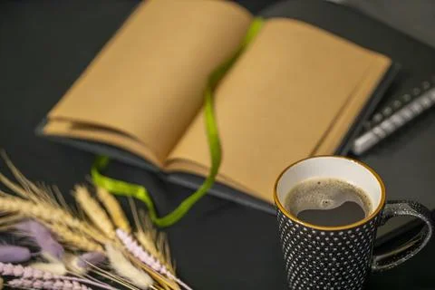 Open notepad, cup of coffee and spikelets on a black background. Stock Photos