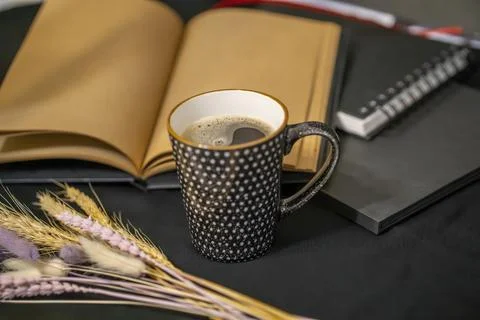 Open notepad, cup of coffee and spikelets on a black background. Stock Photos