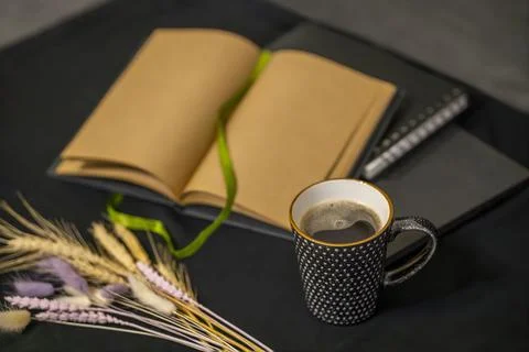 Open notepad, cup of coffee and spikelets on a black background. Stock Photos