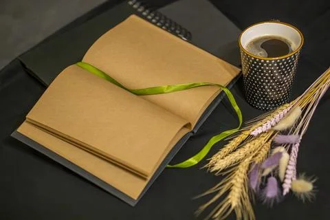 Open notepad, cup of coffee and spikelets on a black background. Foto stock