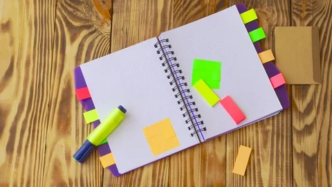 Open notepad is falling down on table / wooden background in slow motion. Stock Footage 77728040