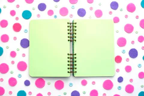 Open Notepad green pages on colored confetti background. Stock Photos