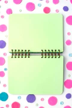 Open Notepad green pages on colored confetti background. Stock Photos