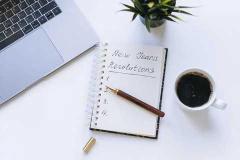 Open notepad with new year resolutions and empty list. Flower, laptop and coffee Stock-Fotos