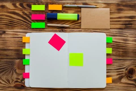 Open notepad with office supplies. Open notepad lies on a wooden desktop Stock Photos