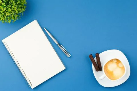 Open notepad with pen, cup of coffee and plant. Stock Photos