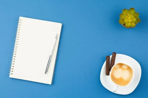 Open notepad with pen, cup of coffee and plant. Foto stock