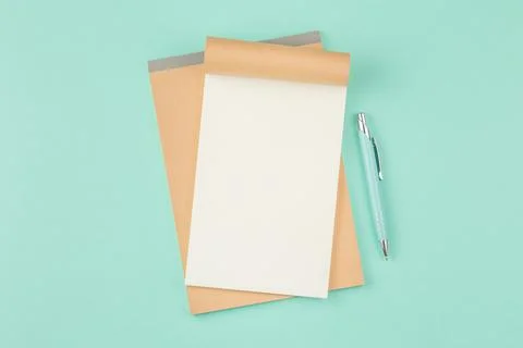 Open notepad with pen on green background Stock-Fotos