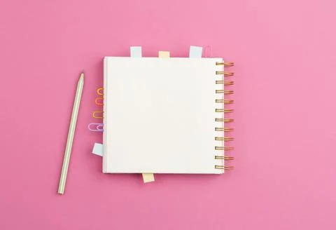 Open notepad with pen on a pink background. Stock Photos