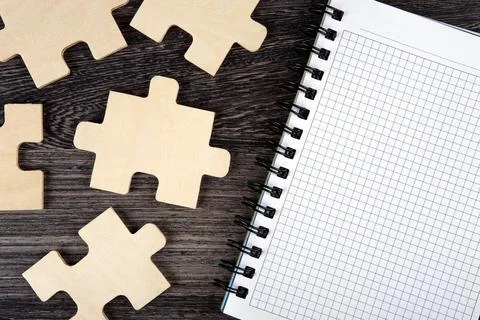 Open notepad with puzzle pieces on a table Stock Photos