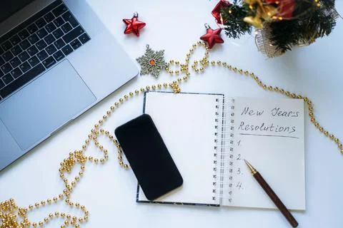 Open notepad with text new year resolutions. and empty list. laptop and smart Stock-Fotos