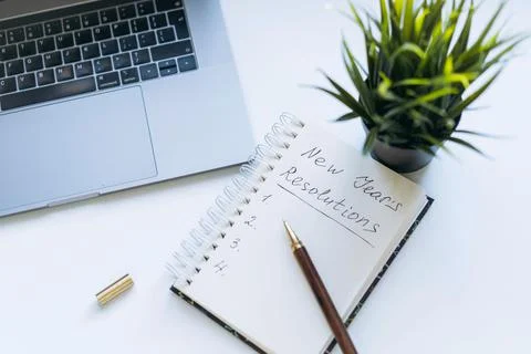 Open notepad with text new year resolutions. and empty list. laptop and smart Stock-Fotos