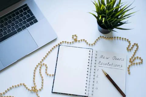 Open notepad with text new year resolutions. and empty list. laptop and smart 写真素材