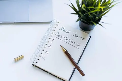 Open notepad with text new year resolutions. and empty list. laptop and Fotos de archivo