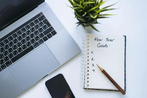 Open notepad with text new year resolutions and empty list. laptop and smartp Stock Photos