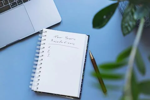 Open notepad with text new year resolutions. and empty list. laptop and Stock-Fotos