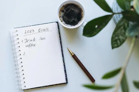 Open notepad with text new year resolutions. and empty list. Flower and cof.. Stock-Fotos