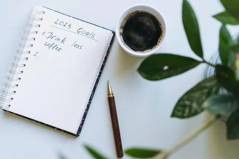 Open notepad with text new year resolutions. and empty list. Flower and cof.. Fotos de archivo