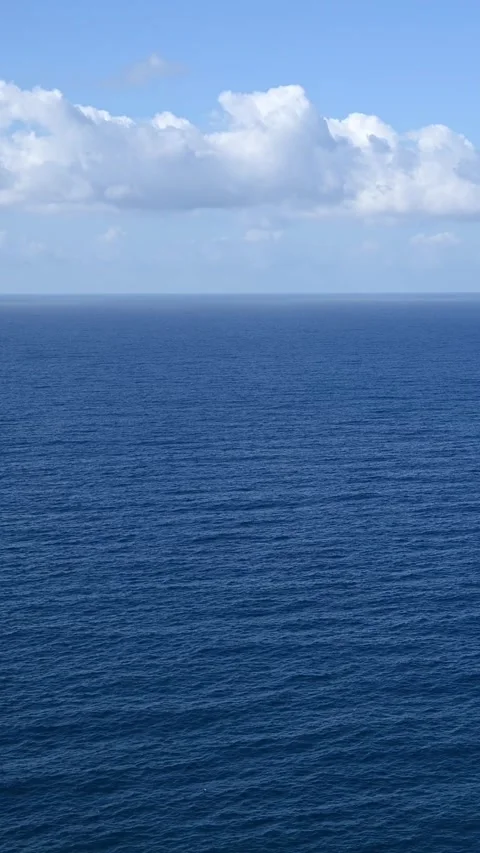 Open ocean waves moving toward horizon under cloudy blue sky Stock Footage 345079622