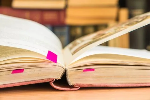 The open old book on the background of a blurred bookcase. Stock Photos