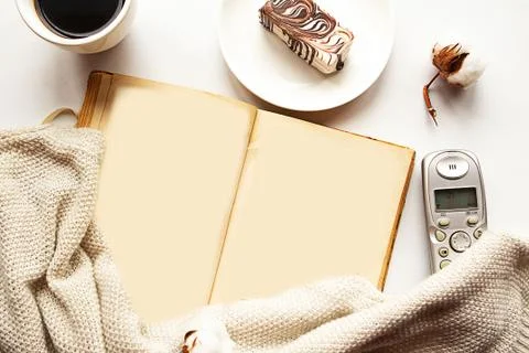 Open old book with empty pages, sweater, coffee cup and chocolate cake on whi Stock Photos