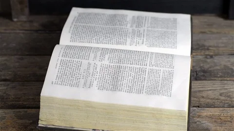 Open old book spinning on a rusty wooden table. Stock Footage 71424572