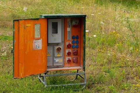 Open old electrical box in grassy field Stock Photos