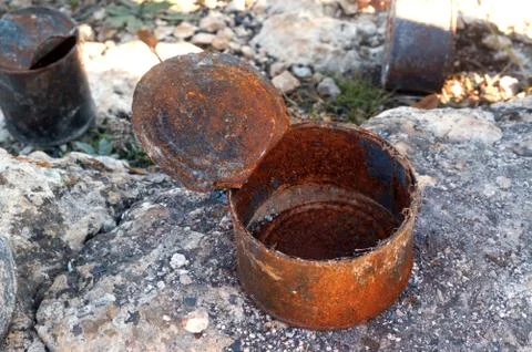 Open old rusty tin cans covered with ash on rock Stock Photos