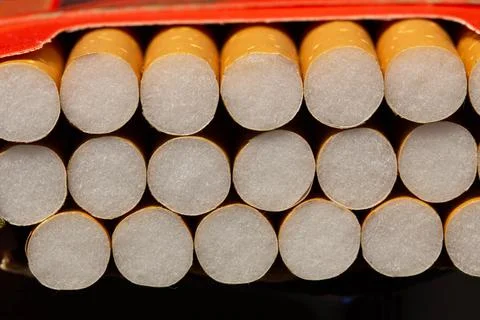 Open pack of cigarettes on black background. Open pack cigarettes. Orange filter Stock Photos