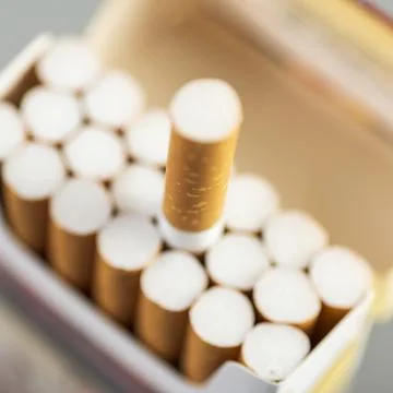 Open pack of cigarettes with one stretched out cigarette close-up Stock Photos
