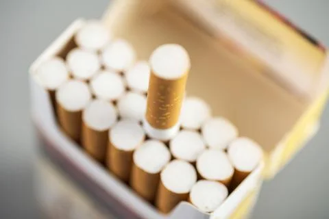Open pack of cigarettes with one stretched out cigarette close-up Stock Photos
