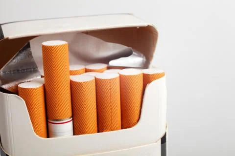 Open pack of cigarettes with orange filter on a white background, place for y Foto stock