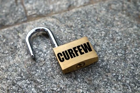 Open padlock, with “Curfew” written.  Stock Photos