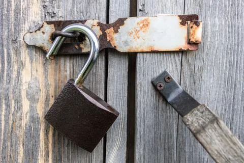 An open padlock hangs on the doors of an old wooden barn Stock Photos