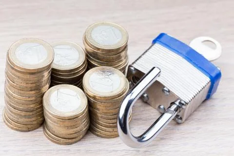 Open padlock next to a stack of coins Stock Photos